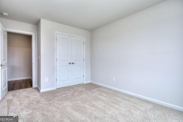 unfurnished bedroom with light carpet and a closet