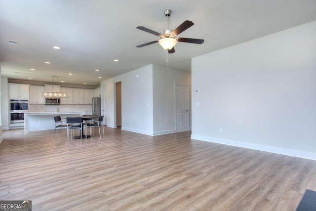 unfurnished living room featuring light hardwood / wood-style floors and ceiling fan