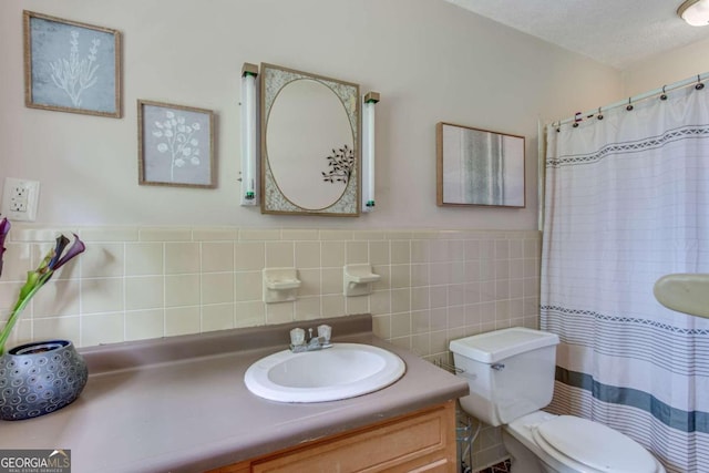 bathroom with tile walls, decorative backsplash, a textured ceiling, toilet, and vanity