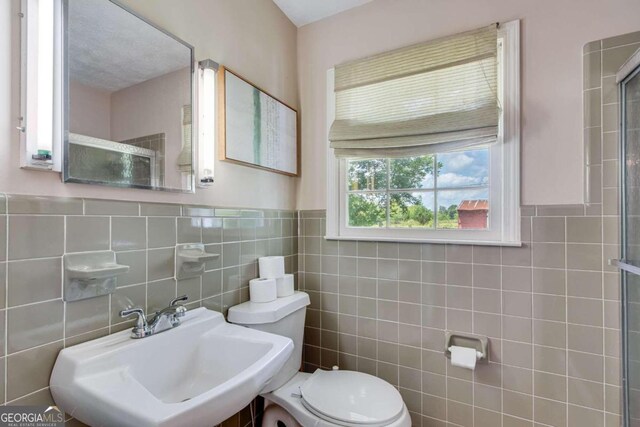 bathroom featuring decorative backsplash, tile walls, toilet, and sink