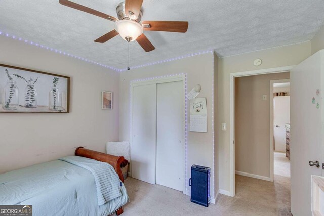 bedroom featuring a textured ceiling, ceiling fan, carpet flooring, and a closet