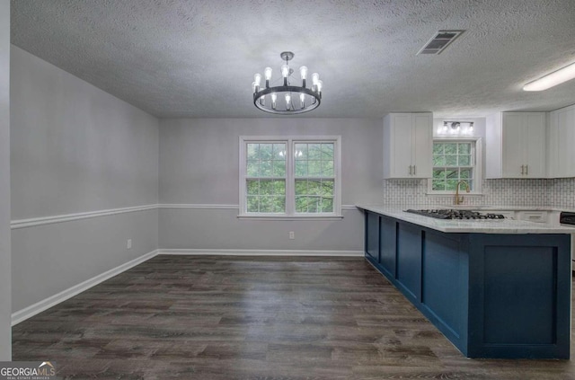 kitchen featuring white cabinetry, decorative backsplash, blue cabinetry, dark hardwood / wood-style floors, and a chandelier