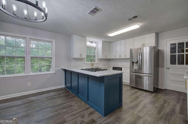 kitchen with kitchen peninsula, stainless steel fridge, dark hardwood / wood-style floors, hanging light fixtures, and white cabinets