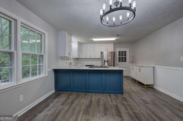 kitchen with kitchen peninsula, stainless steel appliances, backsplash, white cabinets, and sink