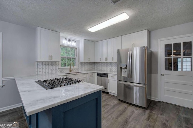 kitchen featuring backsplash, kitchen peninsula, sink, stainless steel appliances, and white cabinets