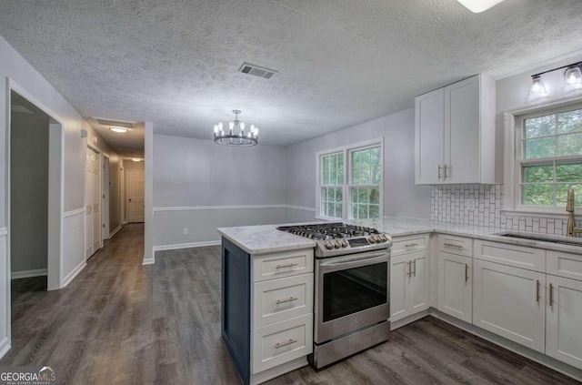 kitchen with kitchen peninsula, dark hardwood / wood-style floors, stainless steel gas stove, white cabinets, and sink