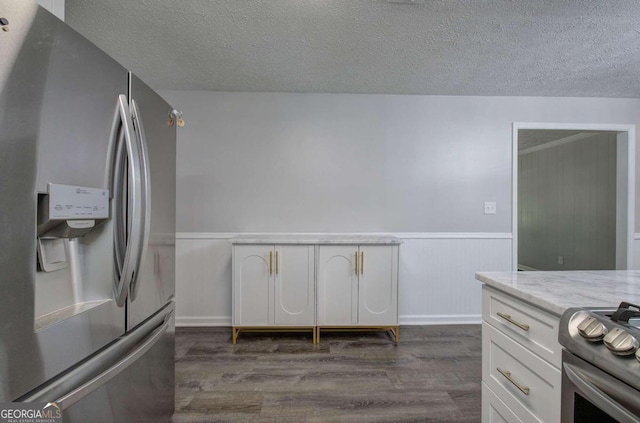 kitchen featuring dark hardwood / wood-style floors, appliances with stainless steel finishes, white cabinetry, and a textured ceiling