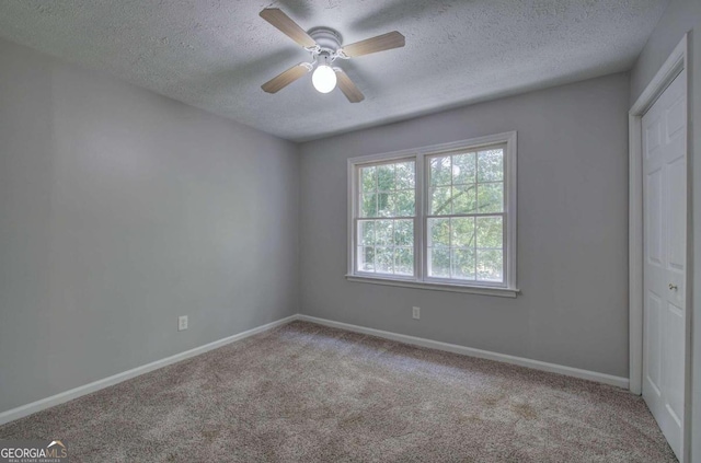 carpeted spare room with ceiling fan and a textured ceiling