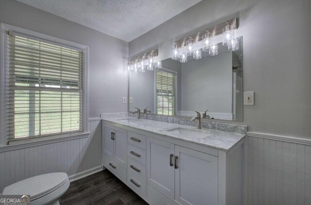 bathroom with a textured ceiling, toilet, vanity, and hardwood / wood-style floors