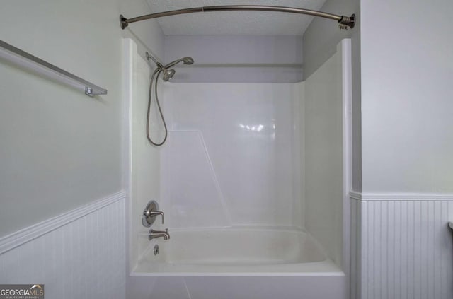 bathroom featuring a textured ceiling and bathing tub / shower combination