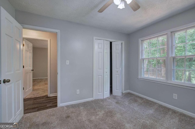 unfurnished bedroom featuring ceiling fan, a textured ceiling, a closet, and carpet flooring