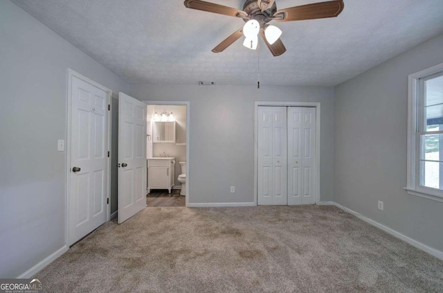 unfurnished bedroom featuring light carpet, ceiling fan, a textured ceiling, and connected bathroom