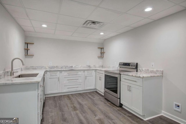 kitchen featuring light hardwood / wood-style floors, electric range, a paneled ceiling, white cabinets, and sink