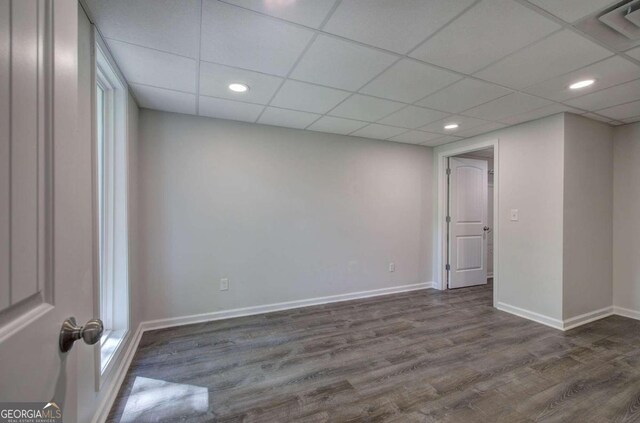 empty room with dark wood-type flooring and a drop ceiling