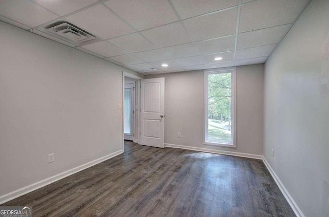 empty room featuring a paneled ceiling and dark hardwood / wood-style floors