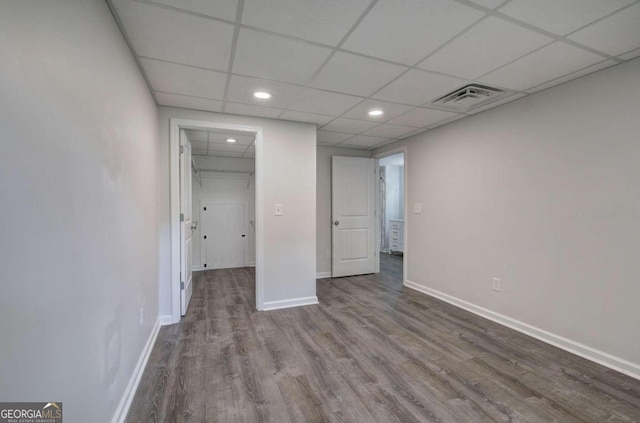 unfurnished bedroom featuring a spacious closet, a paneled ceiling, a closet, and hardwood / wood-style flooring