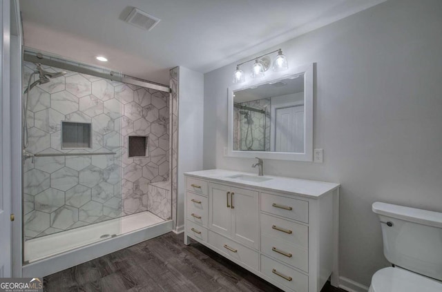 bathroom with toilet, a shower with shower door, hardwood / wood-style flooring, and vanity