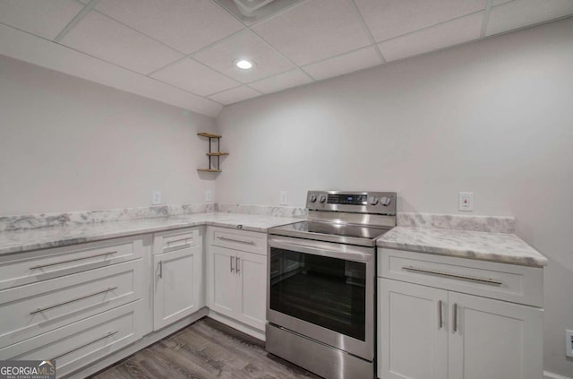 kitchen with electric range, white cabinets, hardwood / wood-style floors, and a drop ceiling