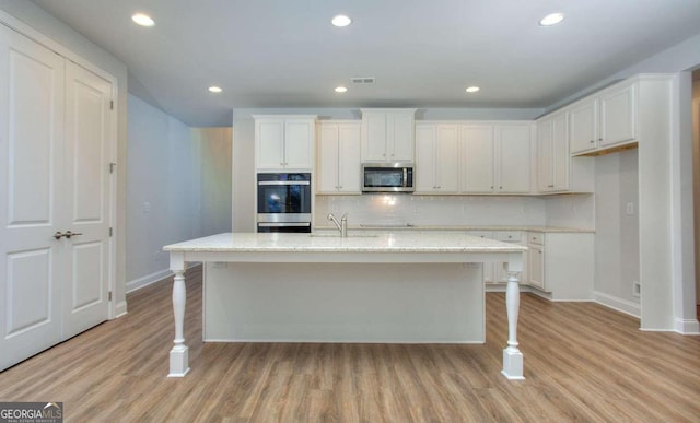 kitchen featuring baseboards, appliances with stainless steel finishes, light wood finished floors, and decorative backsplash
