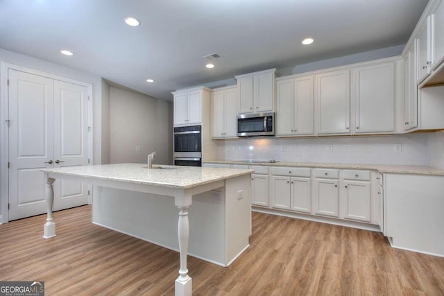 kitchen with light wood finished floors, a sink, appliances with stainless steel finishes, and visible vents