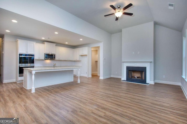 kitchen featuring ceiling fan, white cabinetry, stainless steel appliances, and light wood-style floors