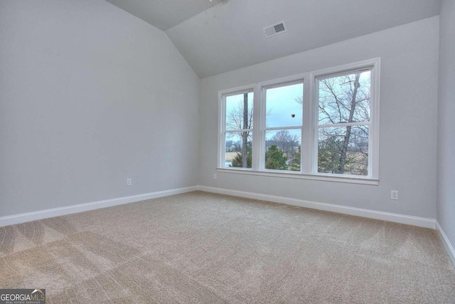 carpeted empty room with lofted ceiling, visible vents, and baseboards