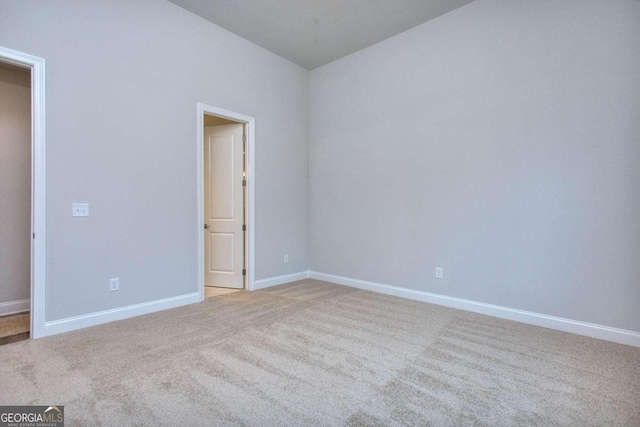 spare room featuring baseboards and light colored carpet