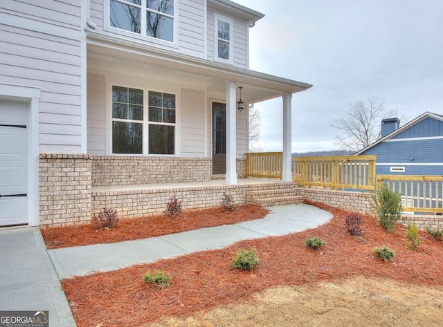 entrance to property featuring covered porch and brick siding