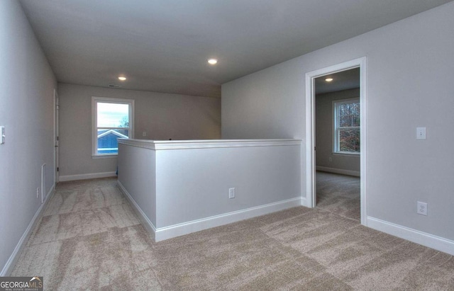 hallway featuring recessed lighting, an upstairs landing, light colored carpet, and baseboards