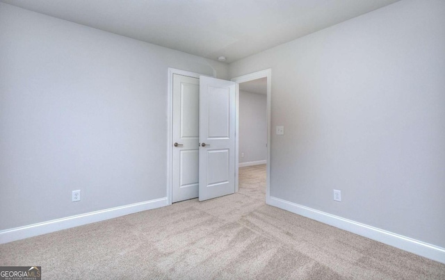empty room featuring baseboards and light carpet