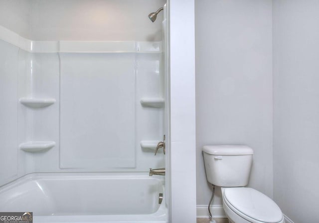 bathroom with toilet, shower / bath combination, and baseboards