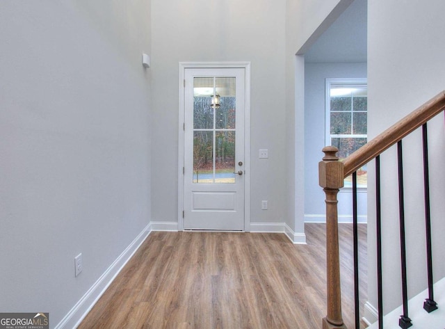 foyer entrance with stairs, wood finished floors, and baseboards