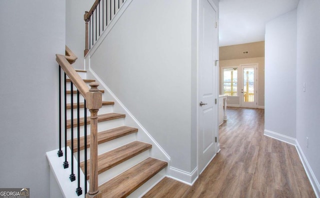 staircase featuring wood finished floors and baseboards