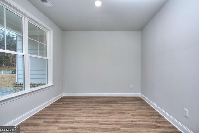 empty room featuring recessed lighting, visible vents, wood finished floors, and baseboards