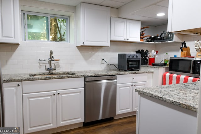 kitchen with decorative backsplash, appliances with stainless steel finishes, light stone countertops, sink, and white cabinetry