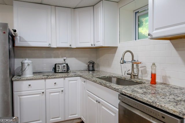 kitchen featuring backsplash, sink, light stone countertops, appliances with stainless steel finishes, and white cabinetry