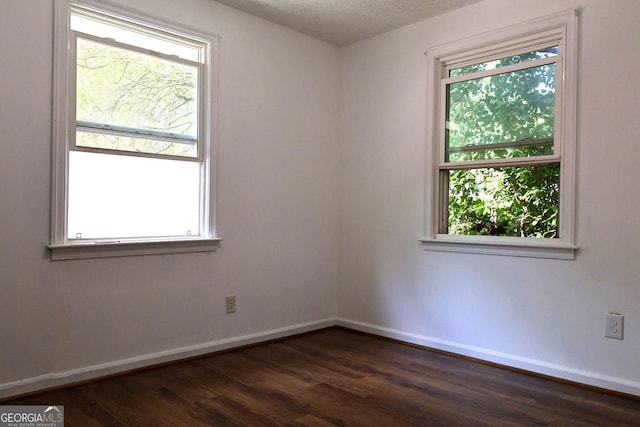 unfurnished room with a textured ceiling and dark wood-type flooring