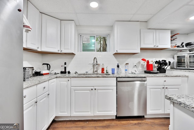 kitchen with appliances with stainless steel finishes, a paneled ceiling, white cabinetry, and sink