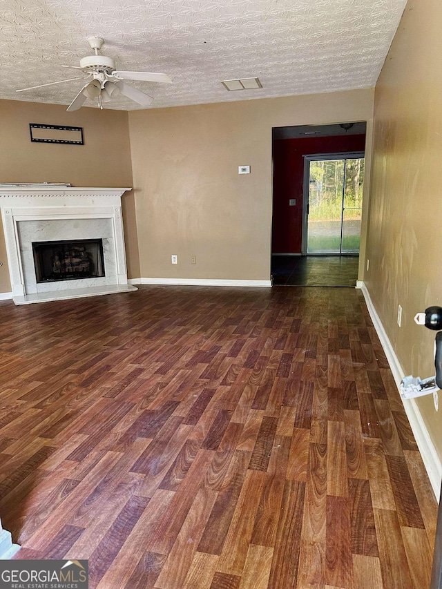 unfurnished living room featuring a fireplace, ceiling fan, dark hardwood / wood-style flooring, and a textured ceiling