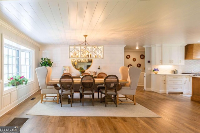 dining room with crown molding, hardwood / wood-style flooring, and a notable chandelier