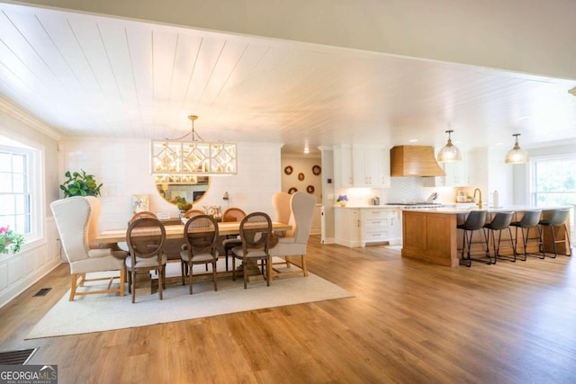 dining area featuring an inviting chandelier, crown molding, hardwood / wood-style flooring, and a wealth of natural light