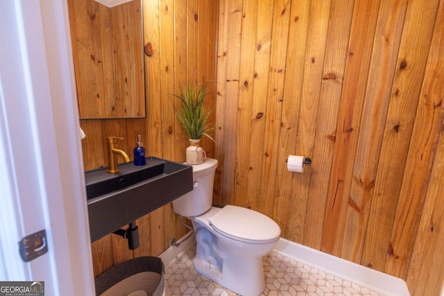 bathroom with wood walls, tile patterned flooring, and toilet