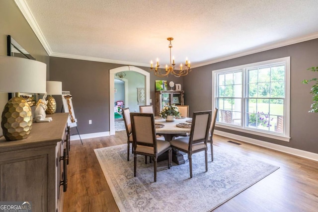 dining space featuring a notable chandelier, a textured ceiling, crown molding, and hardwood / wood-style floors