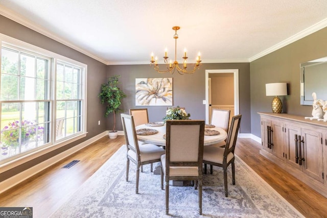 dining space with ornamental molding, an inviting chandelier, and wood-type flooring