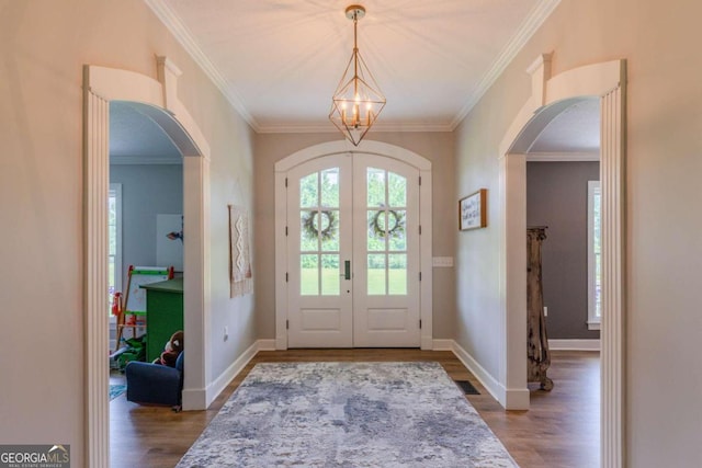 foyer entrance with french doors, crown molding, hardwood / wood-style floors, and a chandelier