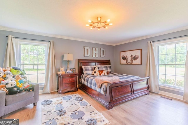 bedroom featuring ornamental molding, multiple windows, and wood-type flooring