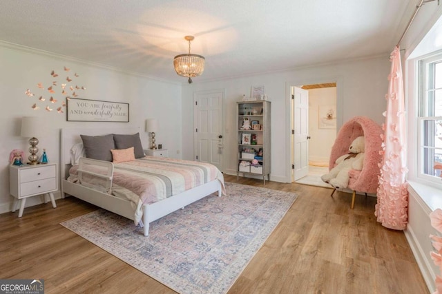 bedroom with an inviting chandelier, wood-type flooring, crown molding, and connected bathroom