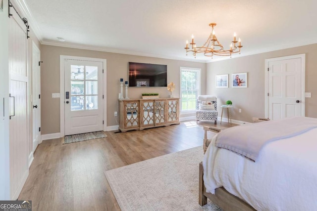 bedroom featuring a notable chandelier, hardwood / wood-style floors, a barn door, and ornamental molding