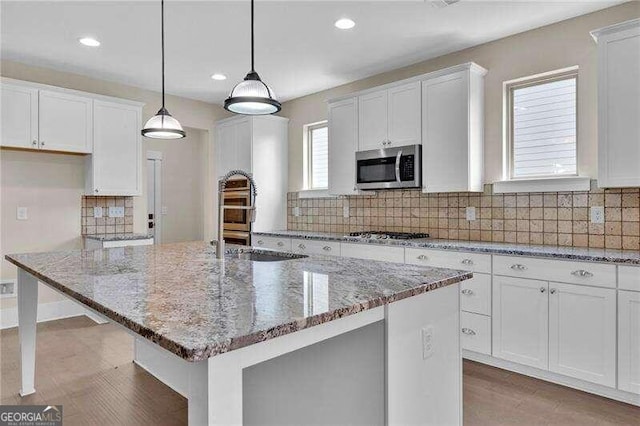 kitchen featuring pendant lighting, a center island, white cabinets, and stainless steel appliances