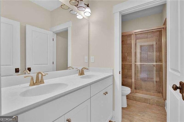 bathroom featuring hardwood / wood-style floors, vanity, toilet, and a shower with shower door